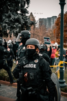 Muž v černé helmě a černé bundě stojící poblíž lidí během dne